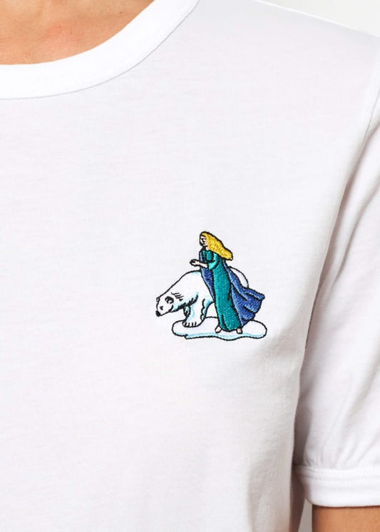 Femme avec un tee shirt gris brodé d'un hibou devant un palais