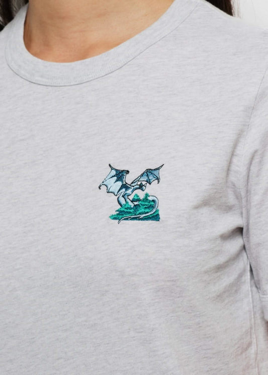 Femme avec un tee shirt gris brodé d'un hibou devant un palais