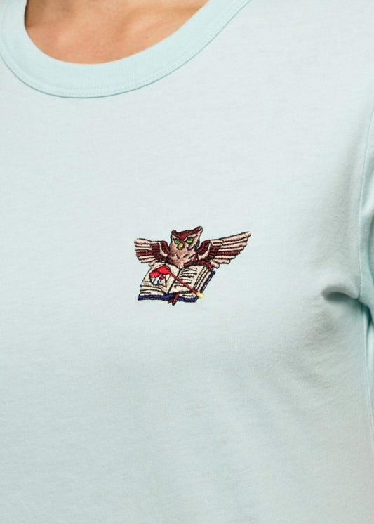 Femme avec un tee shirt gris brodé d'un hibou devant un palais