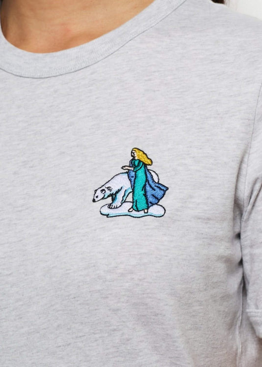 Femme avec un tee shirt gris brodé d'un hibou devant un palais