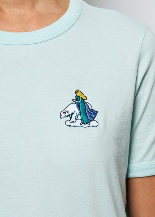 Femme avec un tee shirt gris brodé d'un hibou devant un palais