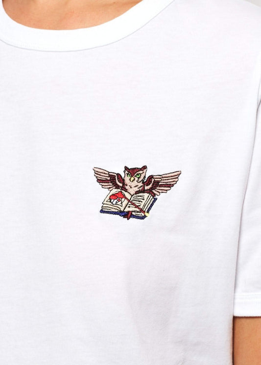 Femme avec un tee shirt gris brodé d'un hibou devant un palais