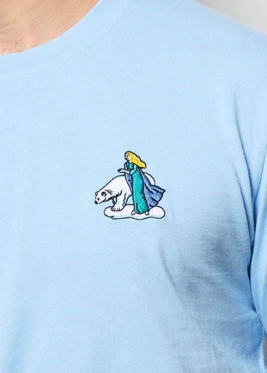 Jeune homme avec un tee shirt brodé d'un dragon lisant un livre dans une forêt
